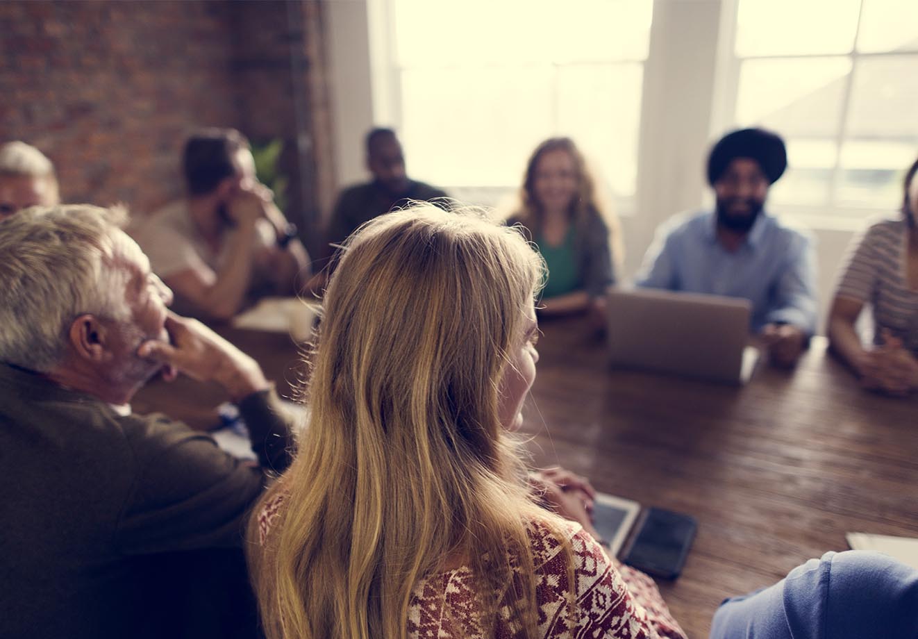 Group of people meeting around a wooden boardroom table