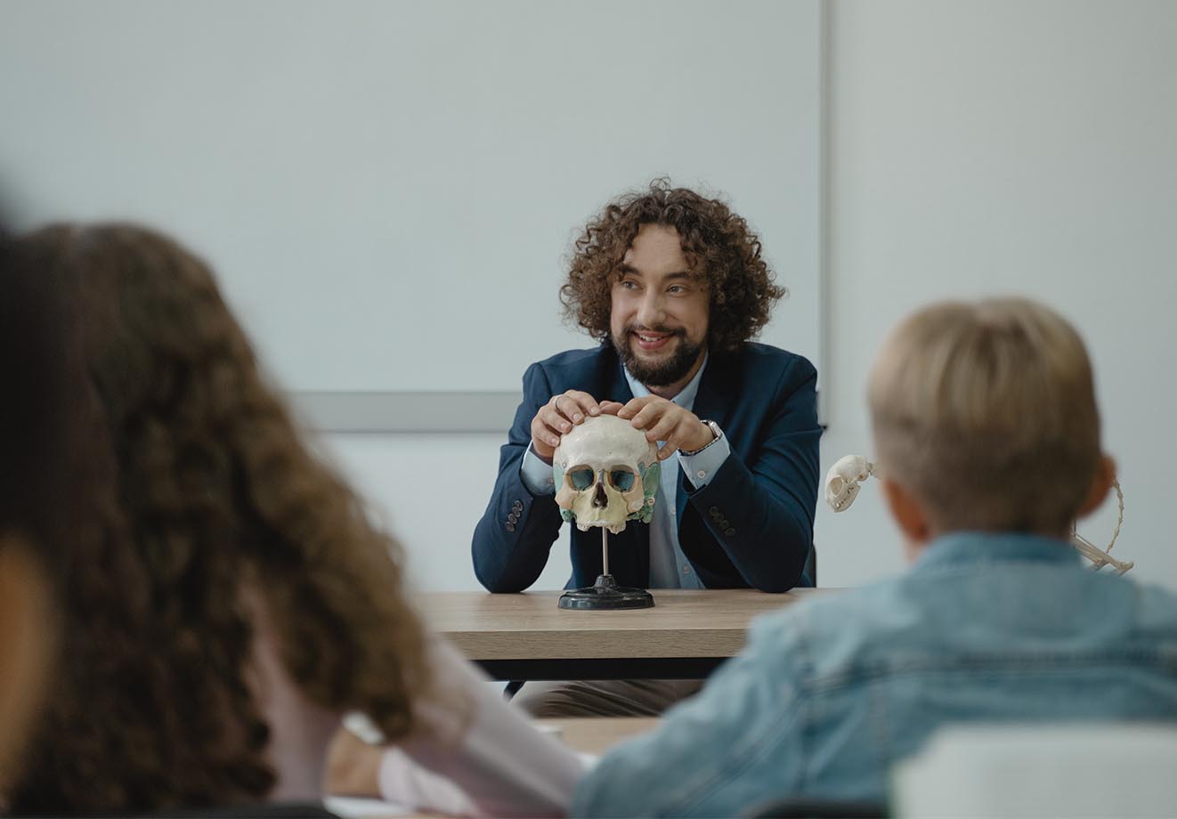 Teacher sitting at the front of the class for a biology lesson
