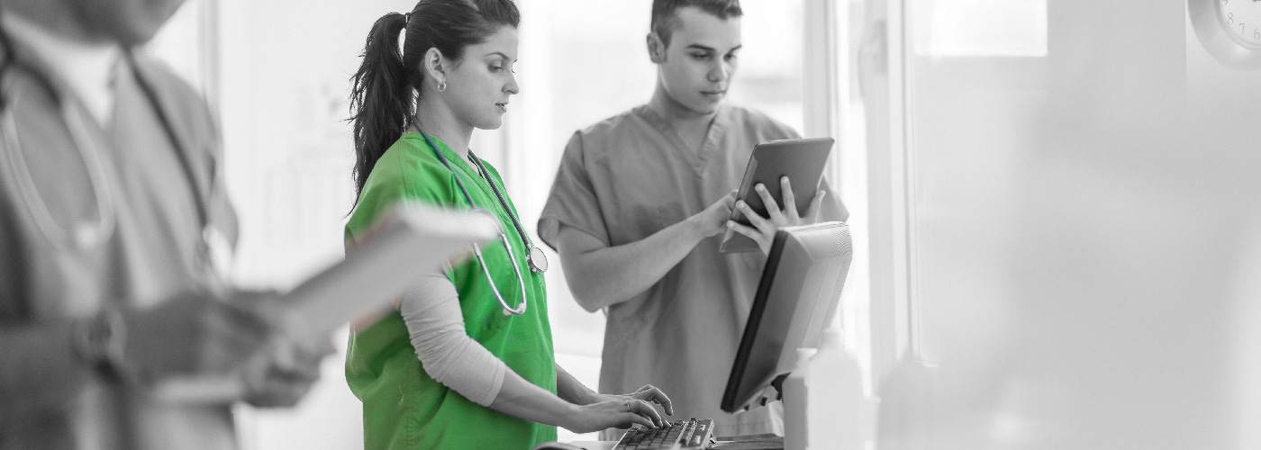 Decorative image: two healthcare workers consulting a computer terminal
