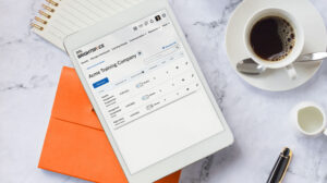 A tablet lying on a table beside a cup of coffee