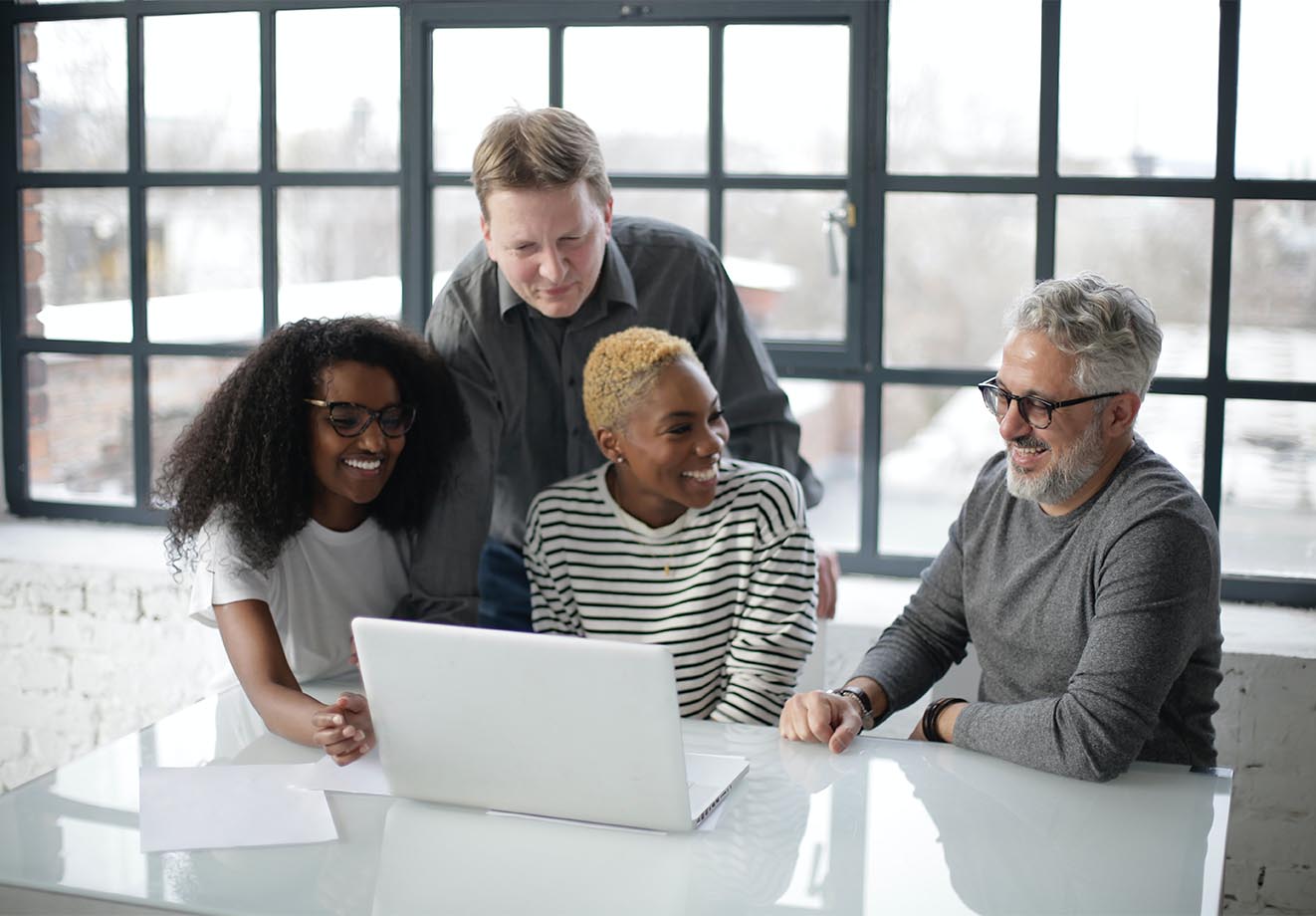 Four people working together around a laptop