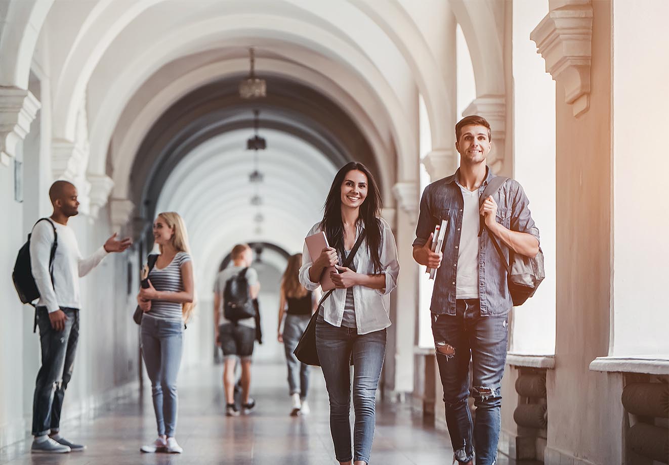 Students walking down an outdoor hall on a college campus.