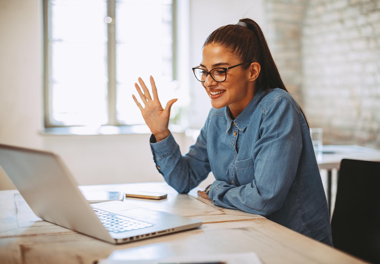 Teacher waving to students through laptop