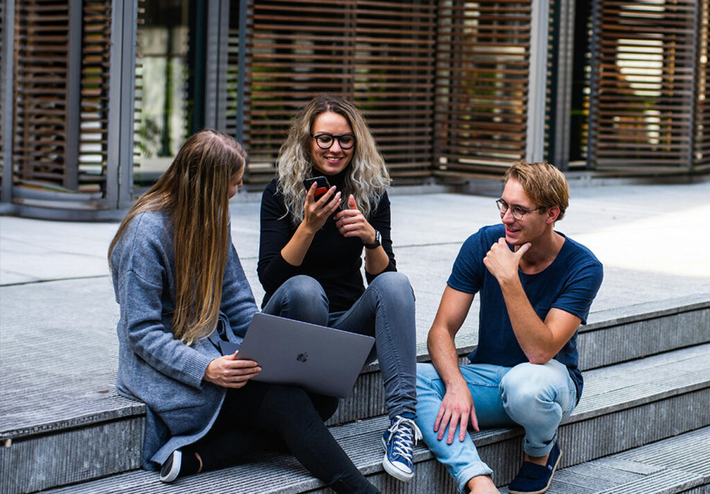 Students sitting on steps gathered around a laptop