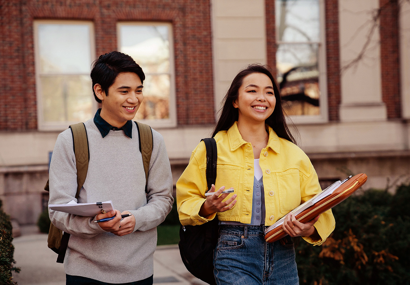 Two students walking outside of school talking with one another
