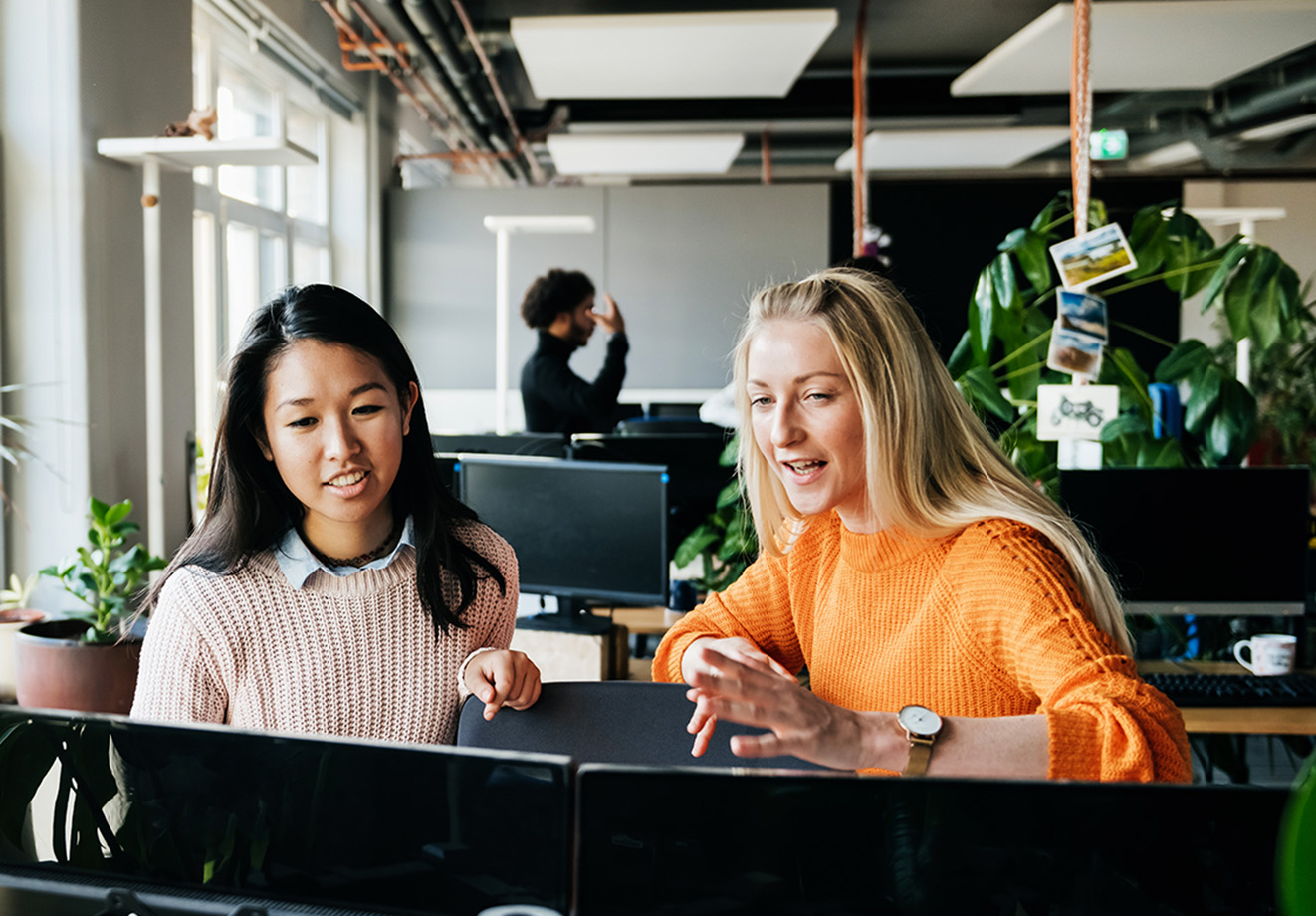 Two women talking to each other in front of computer