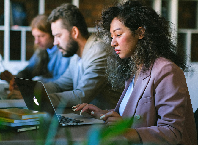 Three focused colleagues working on laptops in office